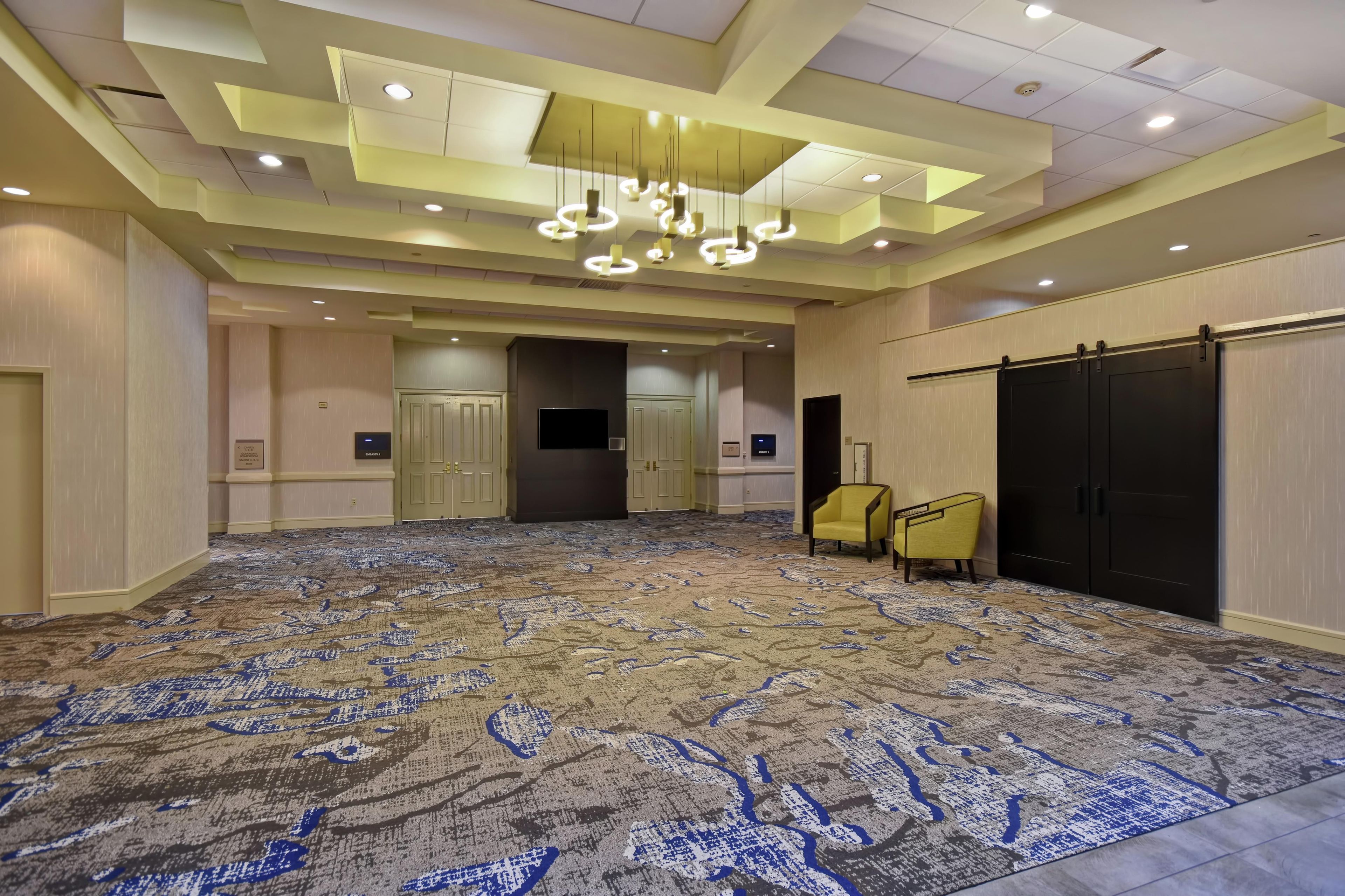 Una habitación espaciosa con alfombra estampada, un candelabro moderno y una puerta corredera.