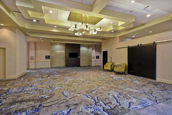 A spacious room with a patterned carpet, a modern chandelier, and a sliding door. - Embassy Suites by Hilton Montgomery Hotel & Conference Ctr (Montgomery)