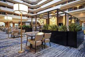 A multi-level hotel lobby with a central seating area, a bar, and a staircase. - Embassy Suites by Hilton Montgomery Hotel & Conference Ctr (Montgomery)