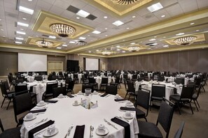 A large banquet hall with multiple round tables set for dining, equipped with white tablecloths, black chairs, and silverware. - Embassy Suites by Hilton Montgomery Hotel & Conference Ctr (Montgomery)