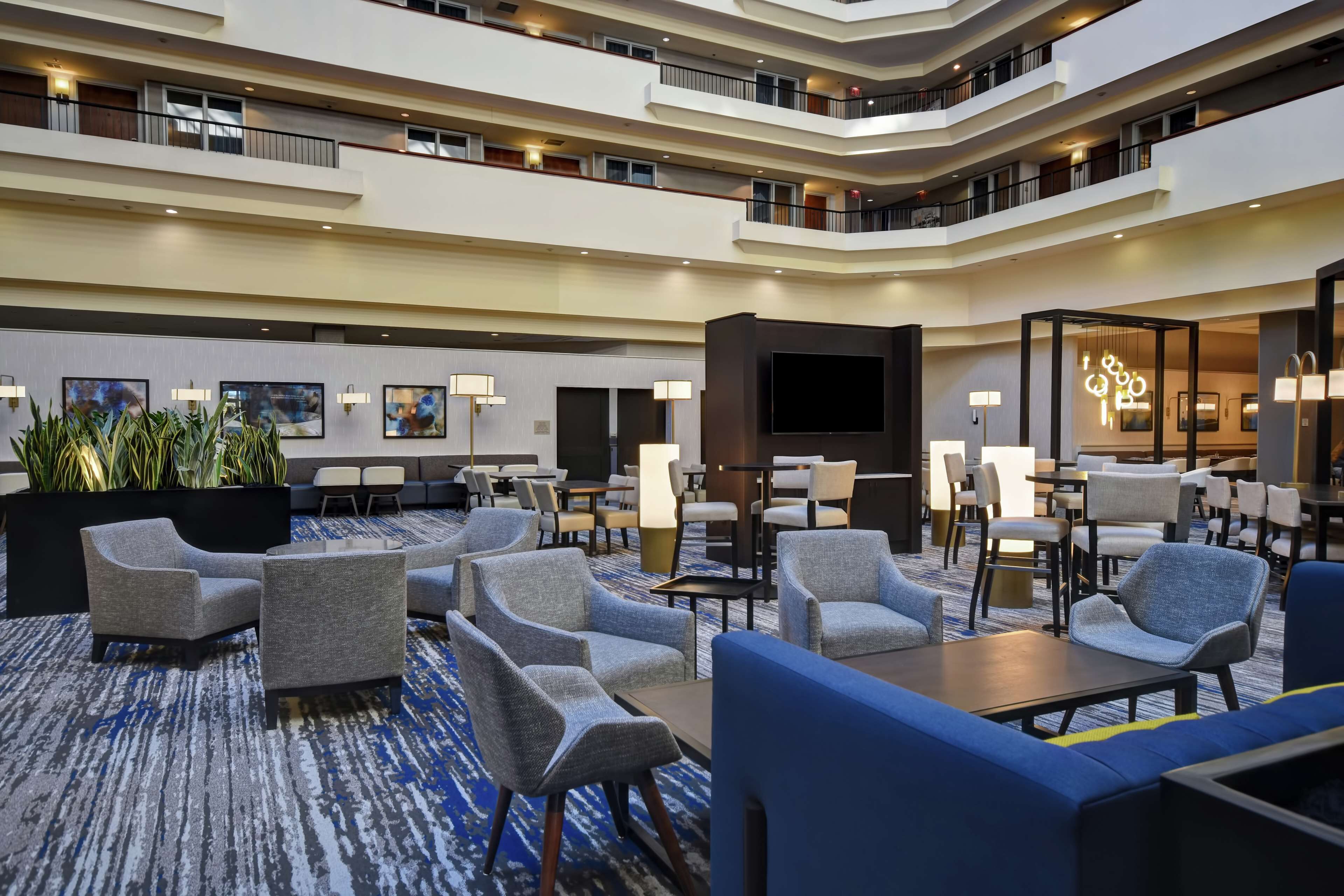 Un hall d’hôtel à plusieurs niveaux, doté d’espaces de détente, d’un grand téléviseur à écran plat et d’un design moderne.