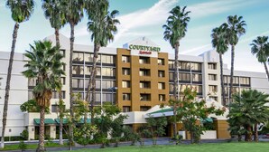 A Courtyard Marriott hotel with a modern design, surrounded by palm trees and a well-maintained lawn. - Courtyard by Marriott Riverside UCR/Moreno Valley Area (Riverside)