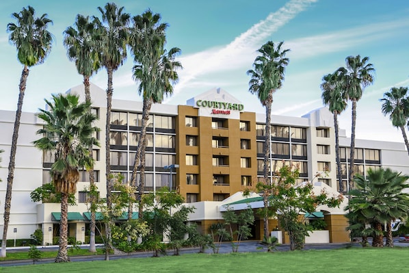A Courtyard Marriott hotel with a modern design, surrounded by palm trees and a well-maintained lawn.