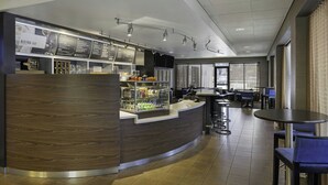 A modern bistro bar with a curved counter, seating area with tables and chairs, and a menu display. - Courtyard by Marriott Riverside UCR/Moreno Valley Area (Riverside)