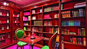 A library with bookshelves, a table, and chairs. - Grange Blooms Hotel (London)