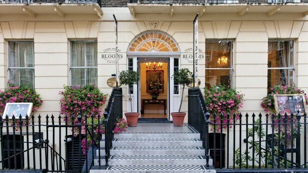 A hotel entrance with a checkered floor, potted plants, and a sign reading "BLOOMS HOTEL". - Grange Blooms Hotel (London)