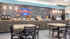A breakfast area with a Baymont sign, kitchen appliances, and seating.
