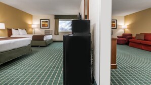 A hotel room with a bed, a desk, a television, a red sofa, and a window with curtains.