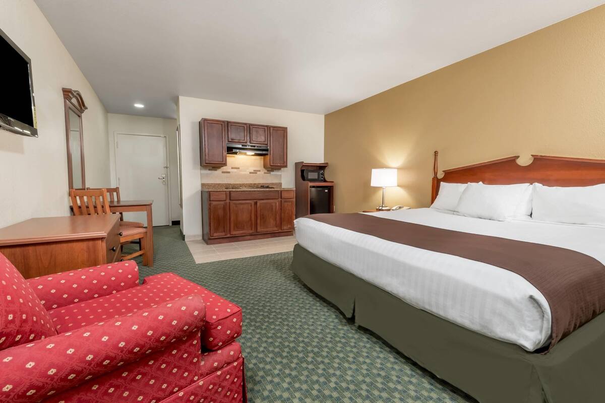 Une chambre d’hôtel équipée d’un lit, d’un bureau, d’une chaise, d’une kitchenette et d’un téléviseur.