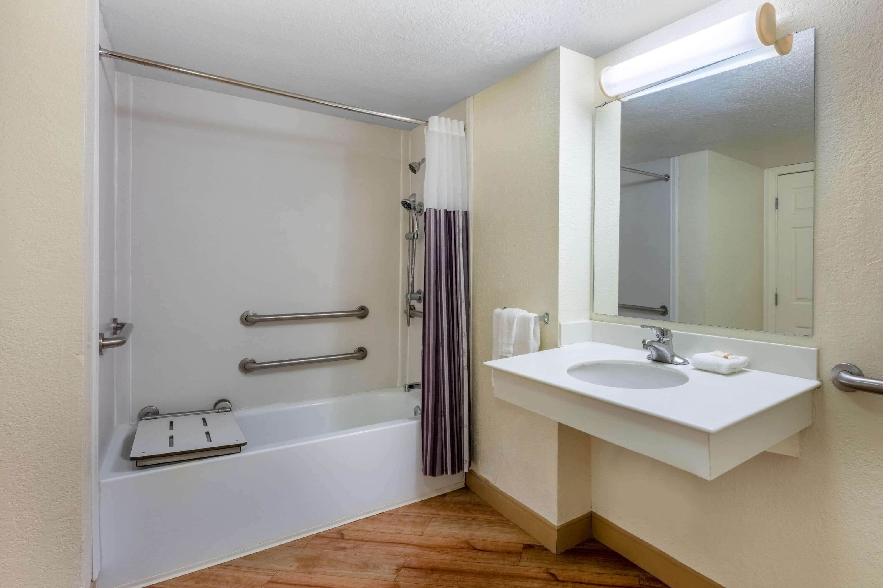 A bathroom with a bathtub, a shower, a sink, and a mirror.