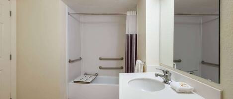 A bathroom with a white sink, mirror, and shower area.