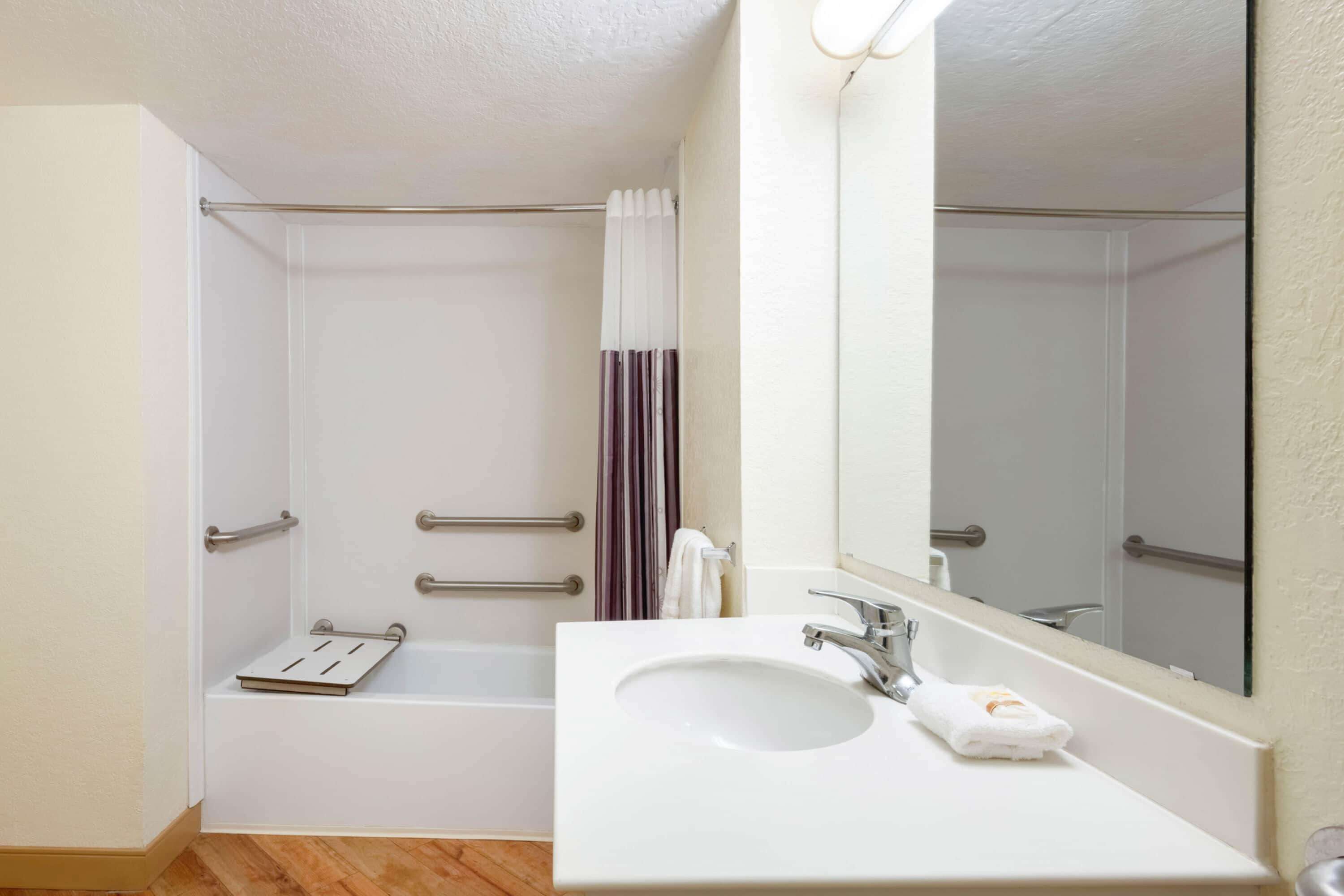 A bathroom with a white sink, mirror, and shower area.