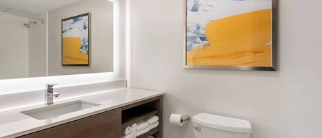 A modern bathroom with a white sink, wooden vanity, and a toilet.