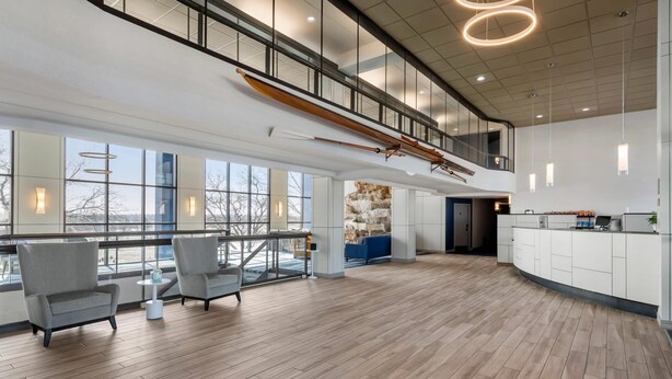 Eine geräumige Hotelhalle mit hoher Decke, einer Holz-Boot-Skulptur und einem modernen Empfangsschalter.