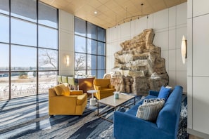 A spacious lobby with large windows, a stone wall feature, and modern seating arrangements. - Comfort Inn Eagan Minneapolis - St. Paul South (Eagan)