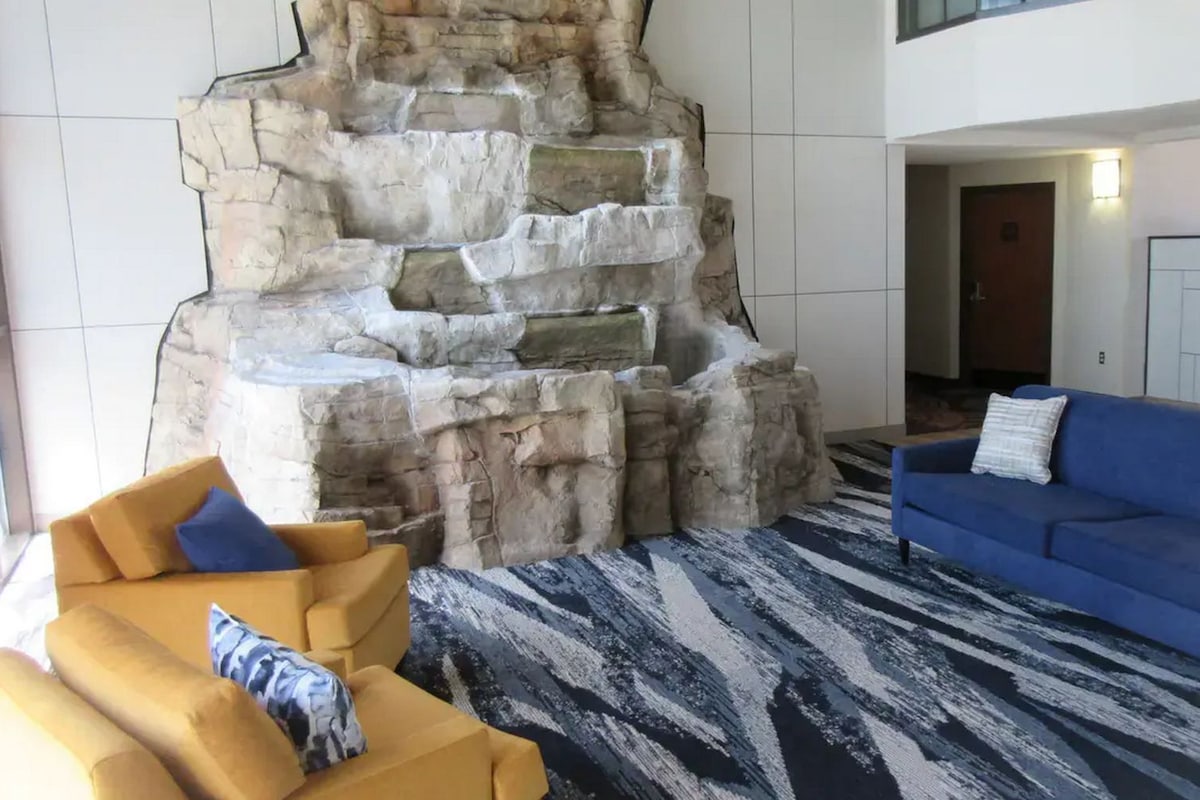 Un vestíbulo con un elemento decorativo de pared de piedra, un sofá azul y una alfombra estampada.