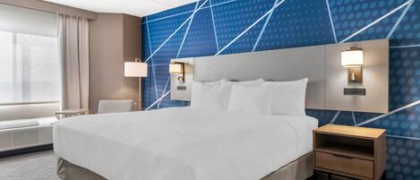 A hotel room with a large bed, bedside tables, a wall with a geometric pattern, and a window with curtains.