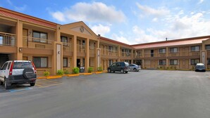 A multi-story motel with a red roof, several balconies, and a parking lot with cars. - Americas Best Value Inn Kingsville (Kingsville)