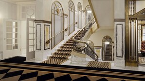 A grand staircase with ornate railings and patterned steps, leading to a room with a large mirror and a leather chair. - Hotel Bristol, a Luxury Collection Hotel, Vienna (Vienna)