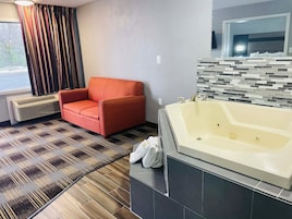 Un baño moderno con una bañera grande, un sillón rojo y un suelo con estampado.