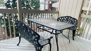 A wooden deck with a metal table and chairs, surrounded by a wooden fence.