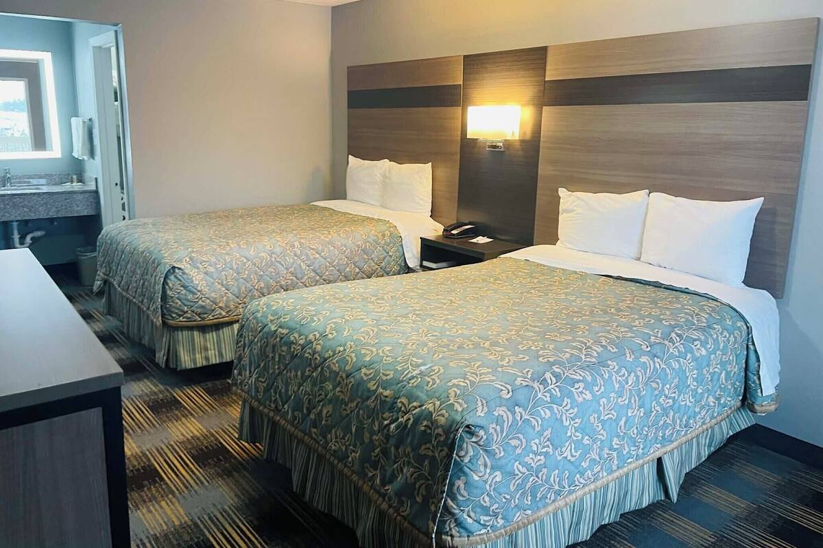 Una habitación de hotel con dos camas, una mesita de noche, un escritorio y un baño.
