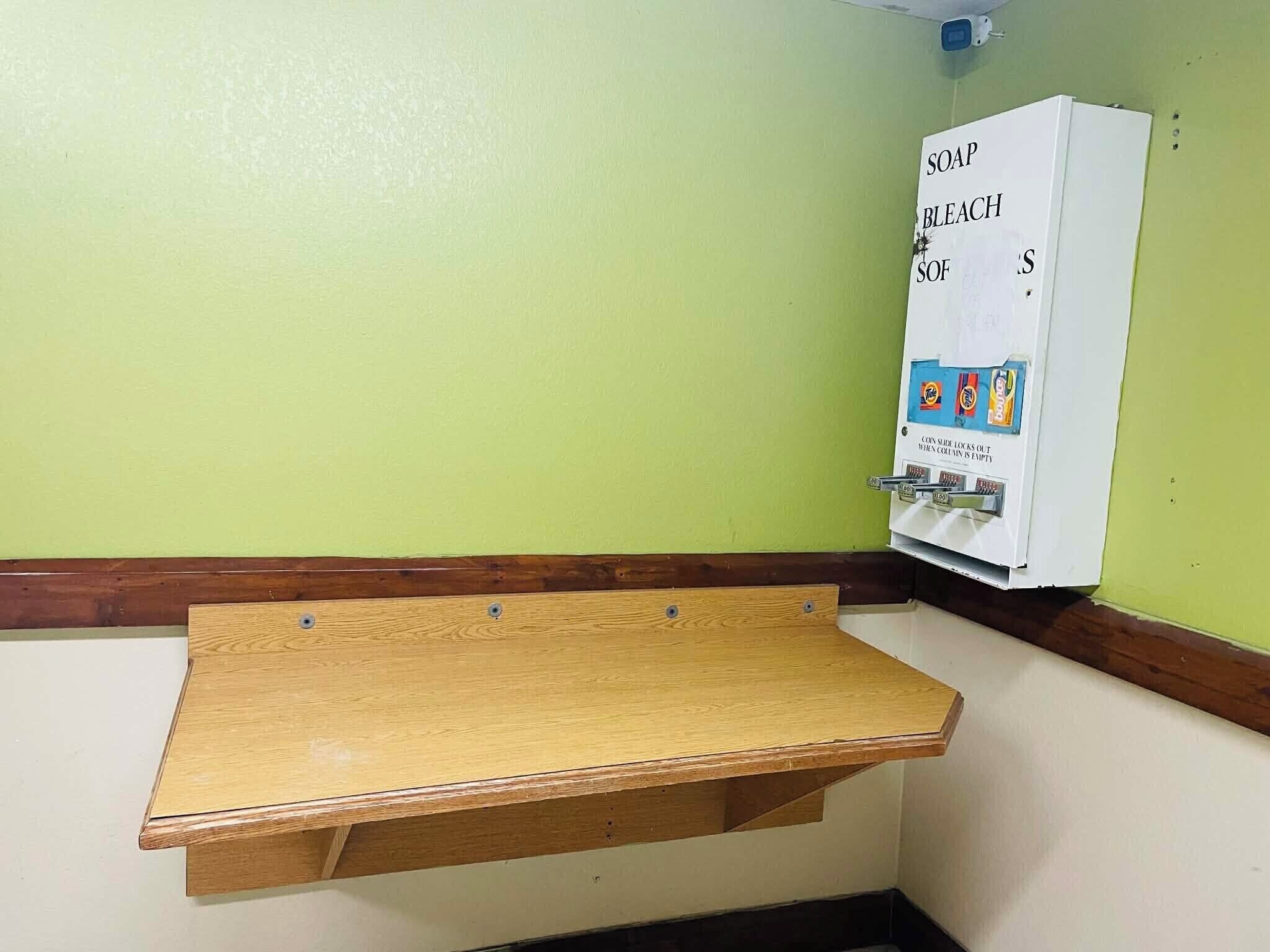 A corner with a wooden shelf and a coin-operated vending machine.