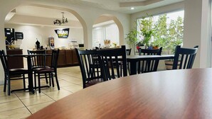 A dining area with a large wooden table and chairs, a kitchen in the background, and a sign that reads "BEAR OIL".