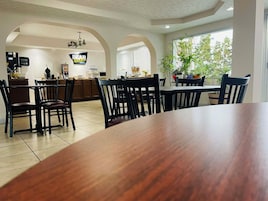 Un comedor con una gran mesa de madera y sillas, una cocina al fondo y un letrero que dice "BEAR OIL".