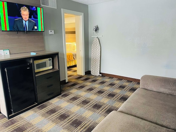 Habitación de hotel con televisión de pantalla plana, minibar, microondas, alfombra estampada y sofá.