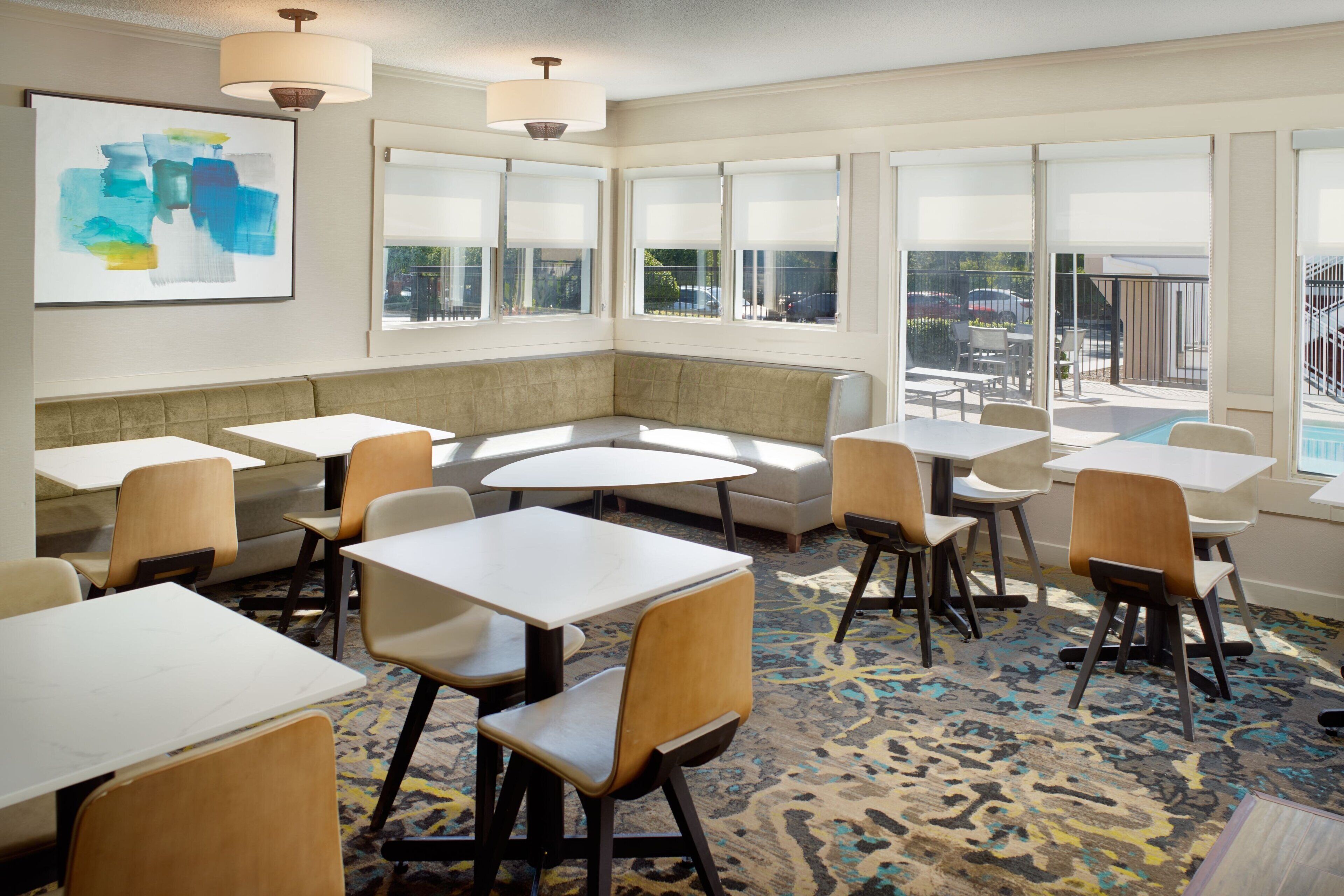 A hotel room with a seating area, tables, and a large window with a view.