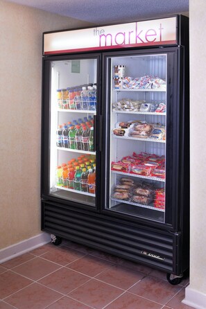 A self-service beverage refrigerator stocked with various drinks and snacks, located in a hallway with tiled flooring. - Residence Inn By Marriott Atlanta Buckhead (Atlanta)