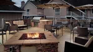 Un patio exterior con un hogar a leña de piedra, asientos y una parrilla.