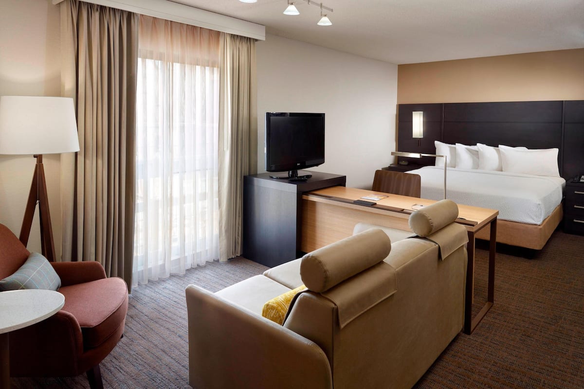 A hotel room with a bed, a TV, a desk, and a sofa.