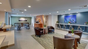 En modern hotellobby med en receptionsdisk, en sittgrupp och en bar.