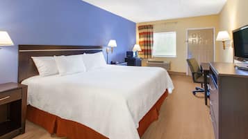 A hotel room with a large bed, a desk, a chair, a television, and a window with curtains.
