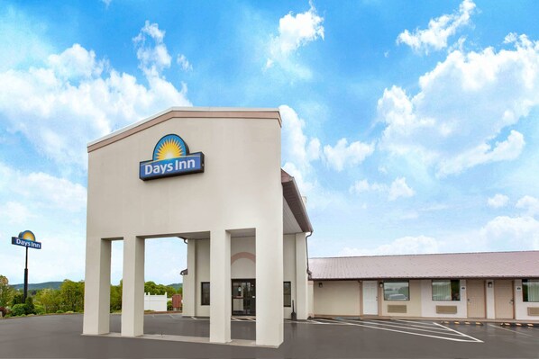 Un hotel Days Inn con un diseño sencillo y moderno, que destaca un cartel llamativo y un estacionamiento.