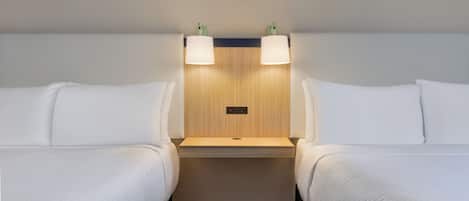 A hotel room with two single beds, a wooden headboard, and two wall-mounted lamps.