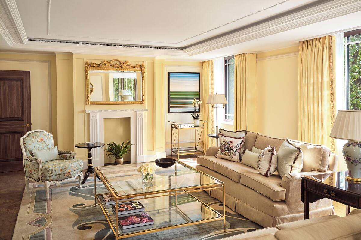 A spacious living room with a sofa, armchairs, a coffee table, and a fireplace.
