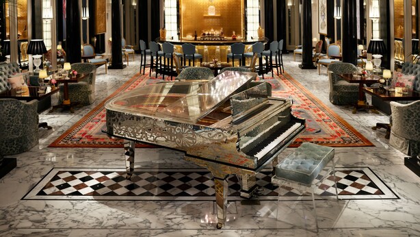 Un lobby lujoso con un piano de cola, asientos cómodos y una zona de bar.