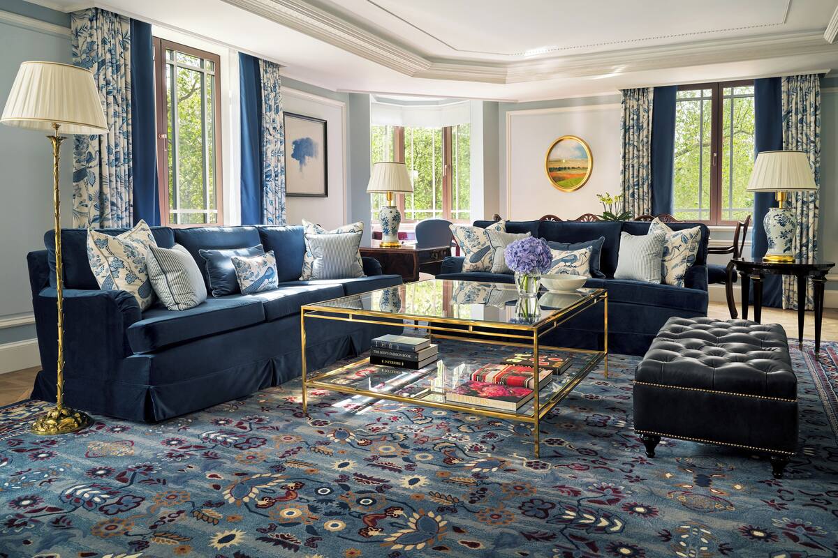Una habitación con un sofá azul, una mesita de centro y una alfombra estampada.