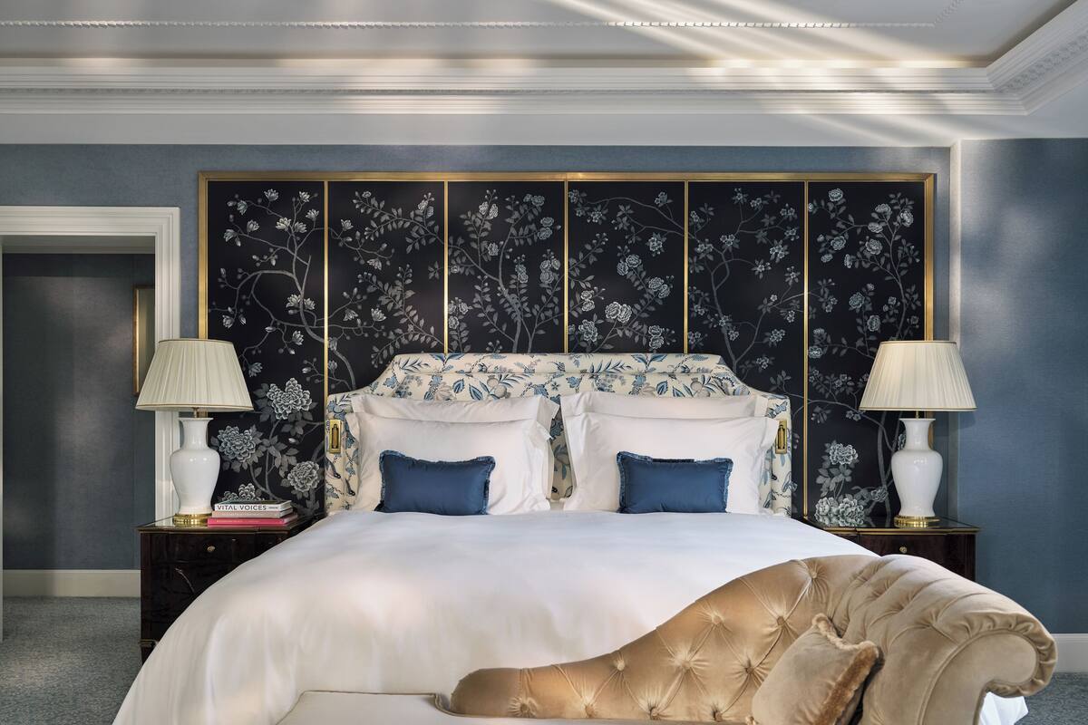 A bedroom with a large bed, two bedside tables, a nightstand, and a bench.