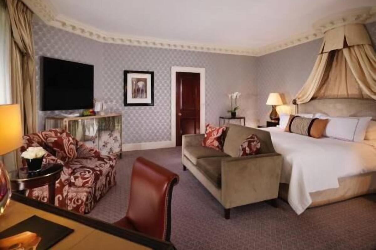 Una habitación de hotel con una cama, un sofá, un televisor, un escritorio y una silla.