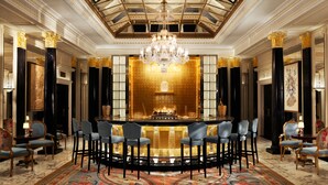 A luxurious hotel lobby with a bar area, ornate chandeliers, and a high ceiling with skylights. - The Dorchester (London)