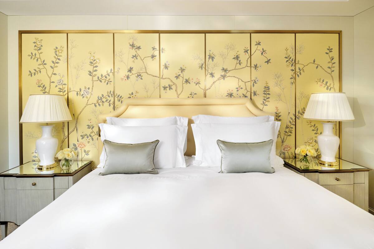 A hotel room with a large bed, two bedside tables with lamps, and a decorative headboard with floral patterns.