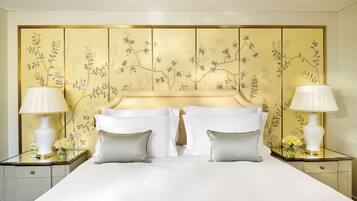 Una habitación de hotel con una cama grande, dos mesitas de noche con lámparas y un cabecero decorativo con motivos florales.