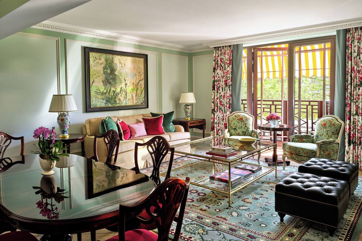 A well-furnished living room with a sofa, armchairs, a coffee table, and a glass-top dining table.