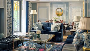 Una sala de estar elegante con un sofá azul, una mesa de centro de vidrio y una lámpara decorativa.