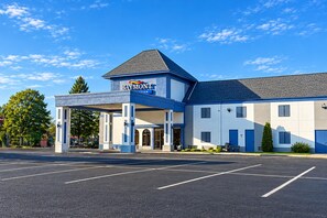 A Baymont Inn with a covered entrance, a parking lot, and a clear blue sky. - Baymont by Wyndham Coldwater (Coldwater)
