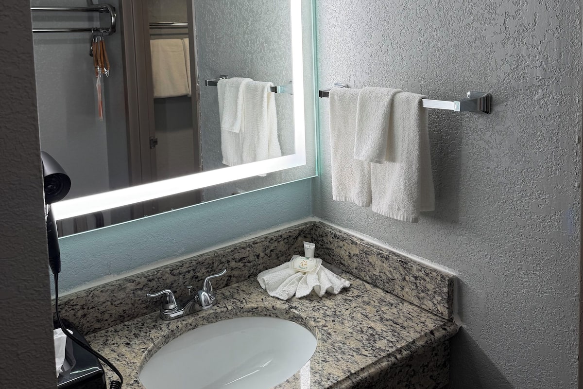 Een bad/douchecombinatie, een haardroger, handdoeken, zeep